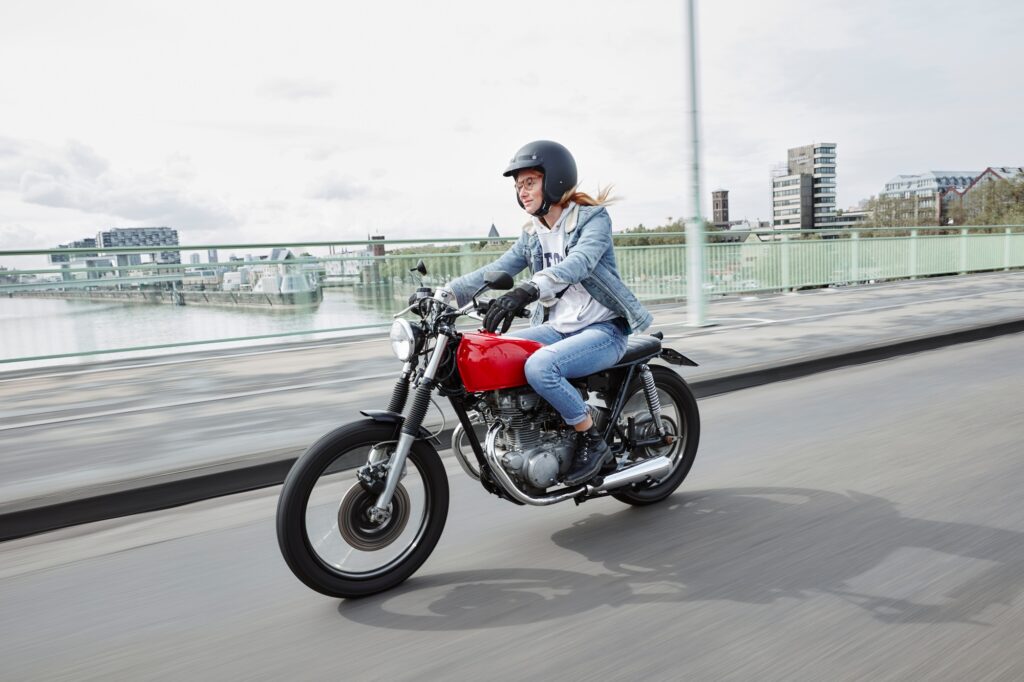 Germany, Cologne, young woman riding motorcycle on bridge